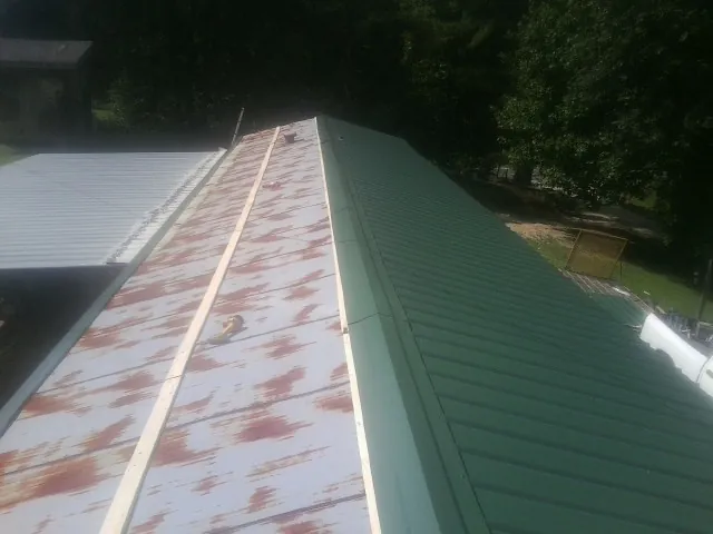 Old rusted panels beside newly installed green metal roofing — Wind Damage Roof Repair by Roofing Brothers in Thompson