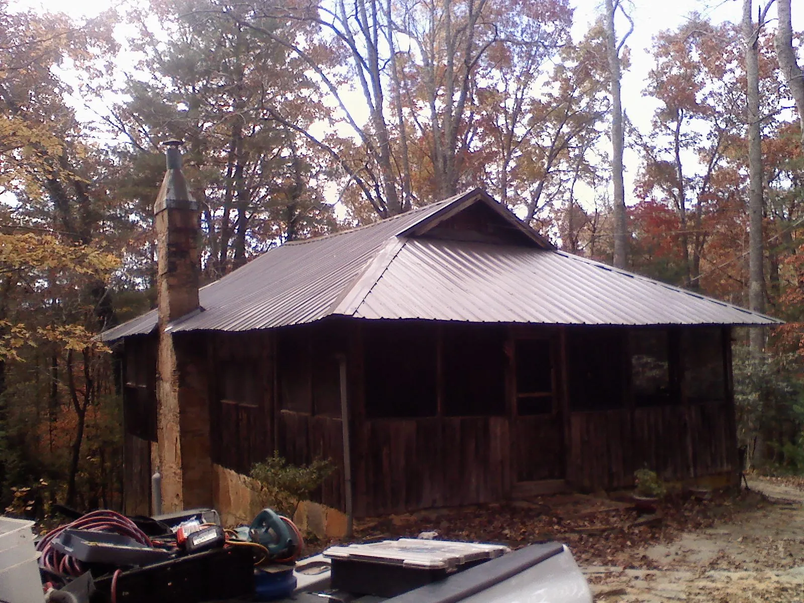 Brown metal hip roof on an old cabin with a stone chimney in Thompson
