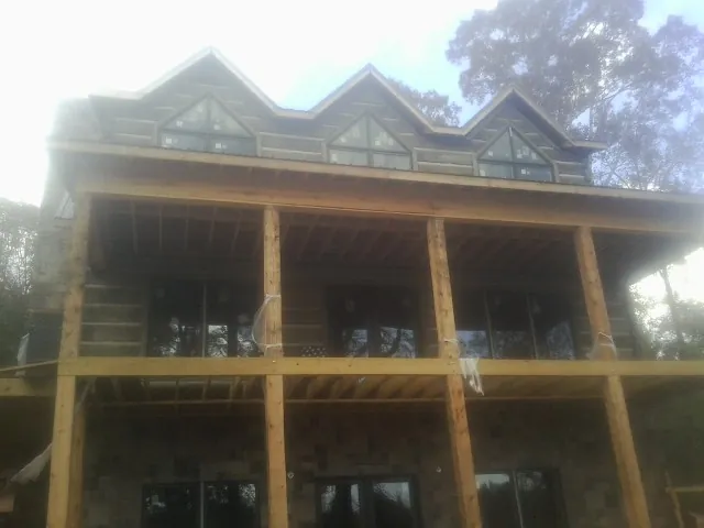 Dormers and porch framing on a large log home under construction — Roof Coating work by our crew in Thompson