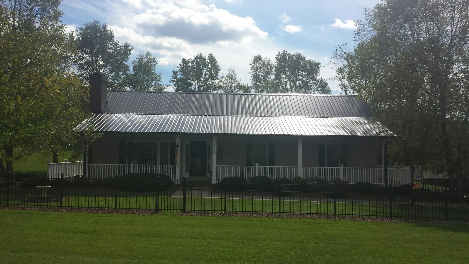 Gray metal roof on a brick ranch with a full width front porch — Gutter Guard Installation work by our crew in Thompson